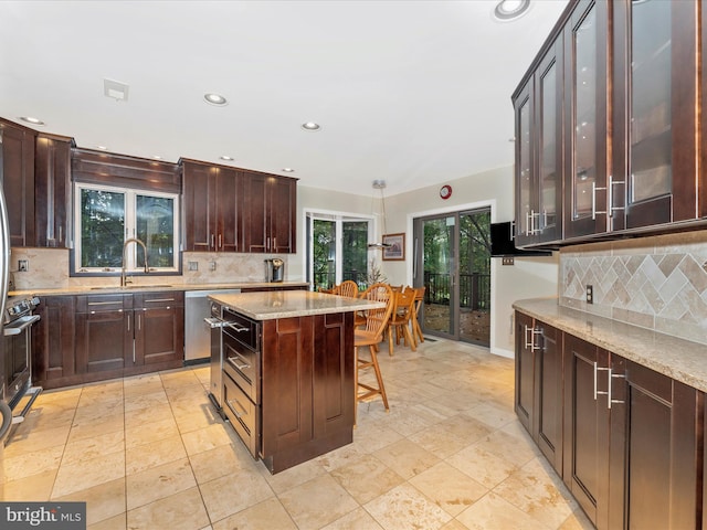 kitchen with dark brown cabinetry, sink, decorative backsplash, and a center island