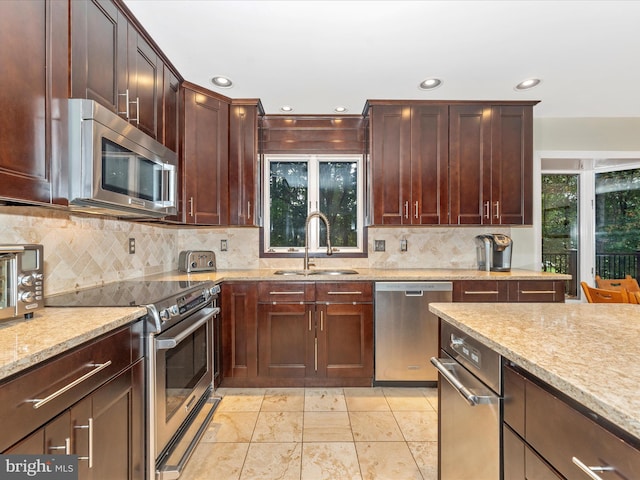 kitchen featuring light stone countertops, backsplash, appliances with stainless steel finishes, and sink