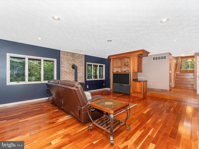 living room featuring hardwood / wood-style floors, a wood stove, and a wealth of natural light