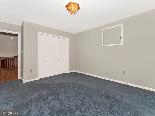 unfurnished bedroom featuring dark carpet and a closet