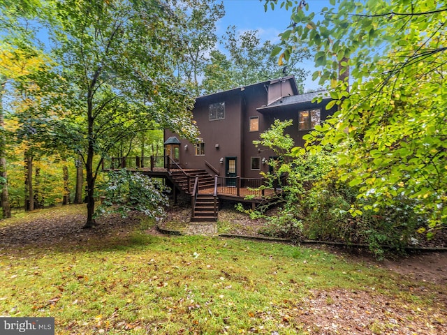 back of property featuring a wooden deck and a yard