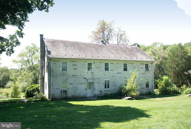 rear view of property featuring cooling unit and a yard