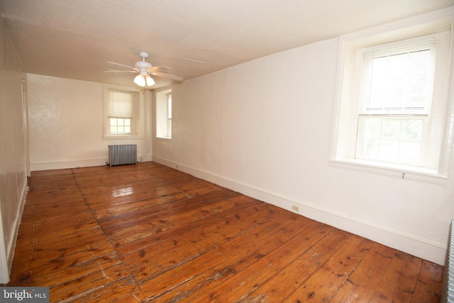 unfurnished room with ceiling fan, dark hardwood / wood-style flooring, and radiator heating unit