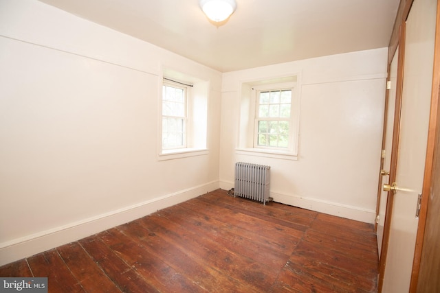 empty room featuring radiator and dark hardwood / wood-style floors