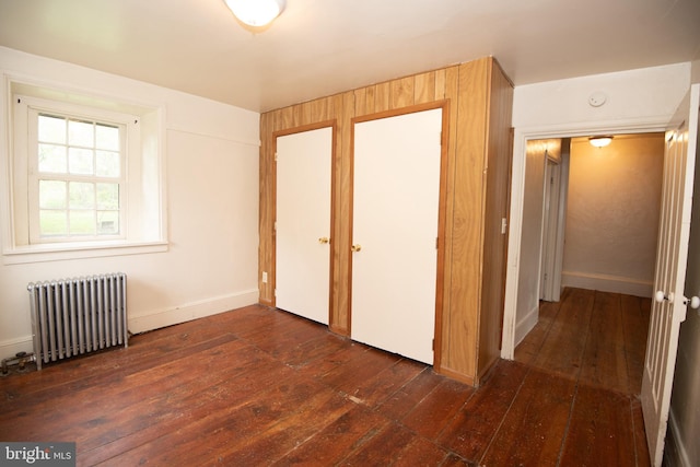 unfurnished bedroom featuring dark wood-type flooring and radiator heating unit