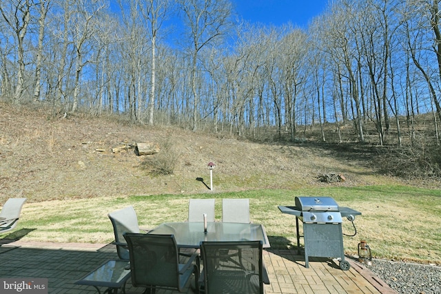 wooden terrace featuring a yard, a patio, outdoor dining space, and grilling area