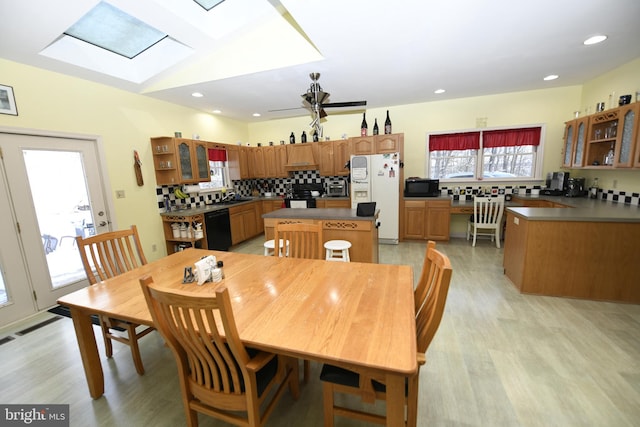 dining area with sink, light hardwood / wood-style flooring, ceiling fan, and a skylight