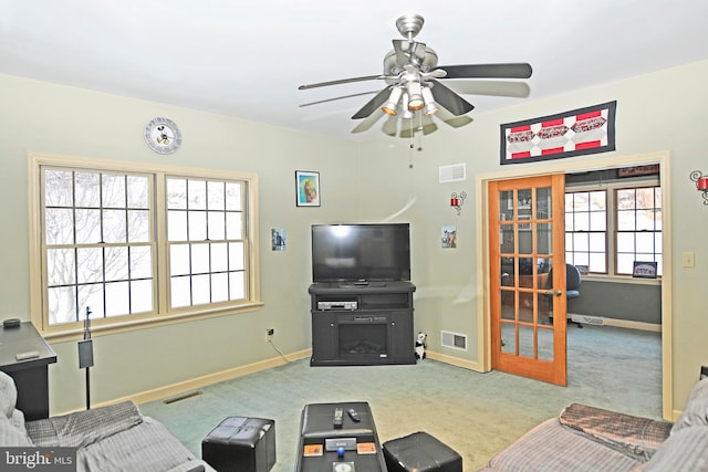 carpeted living area featuring baseboards, visible vents, and a ceiling fan