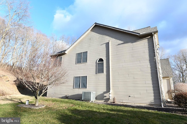 rear view of property with a yard and central air condition unit