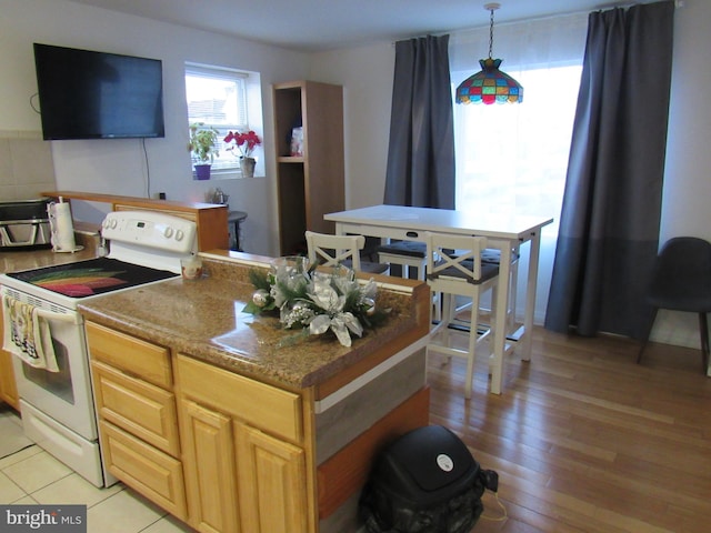 kitchen with light hardwood / wood-style flooring, decorative light fixtures, electric range, and stone countertops