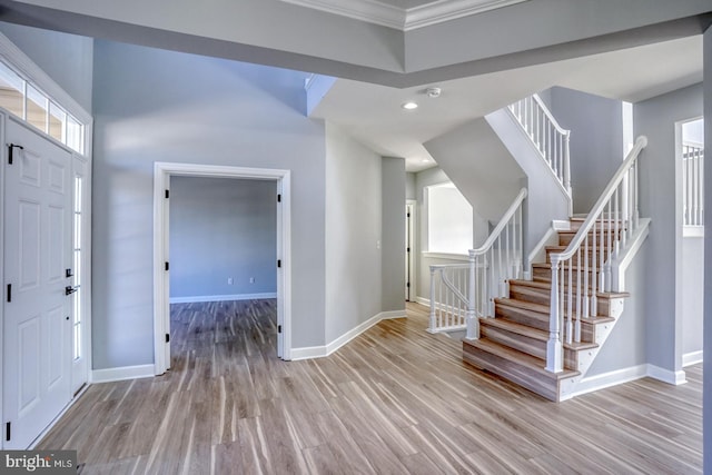 foyer entrance with ornamental molding and light wood-type flooring