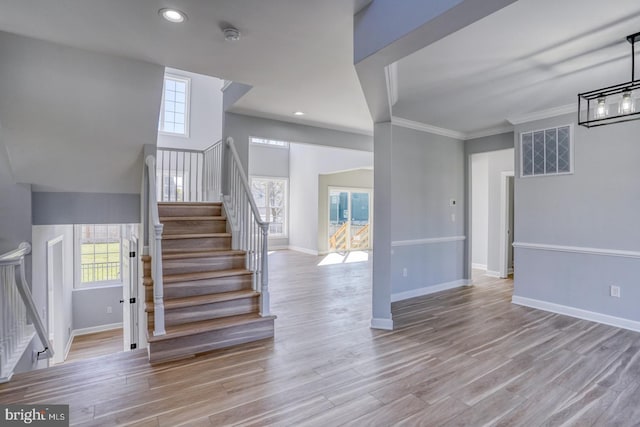 stairs with wood-type flooring and ornamental molding