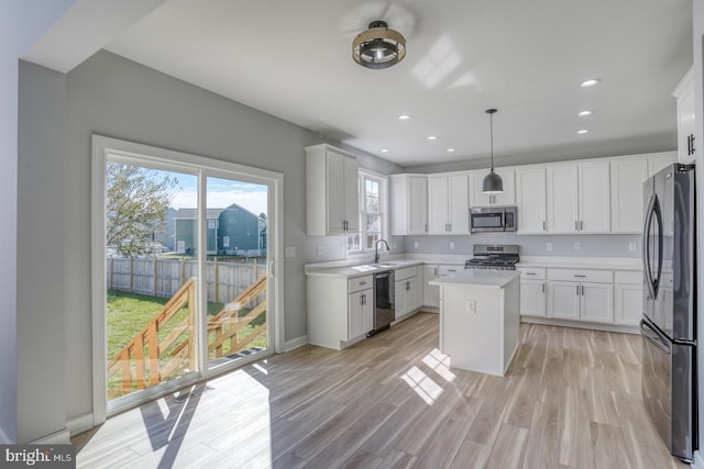 kitchen with stainless steel appliances, a center island, decorative light fixtures, and white cabinets