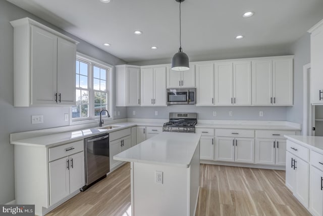 kitchen with white cabinets, appliances with stainless steel finishes, a center island, sink, and decorative light fixtures