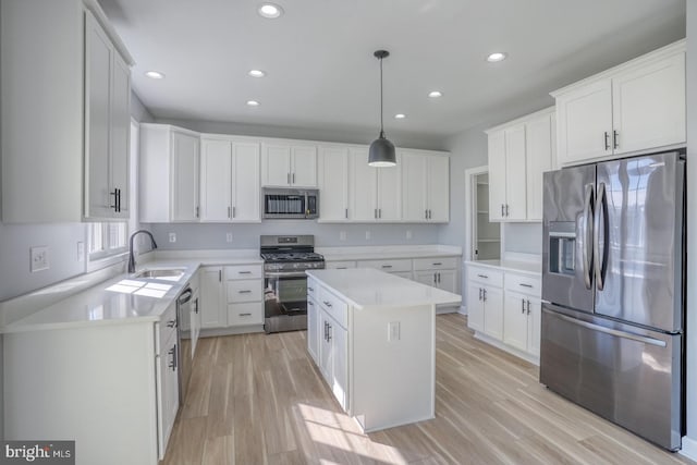 kitchen featuring sink, a center island, hanging light fixtures, white cabinetry, and stainless steel appliances