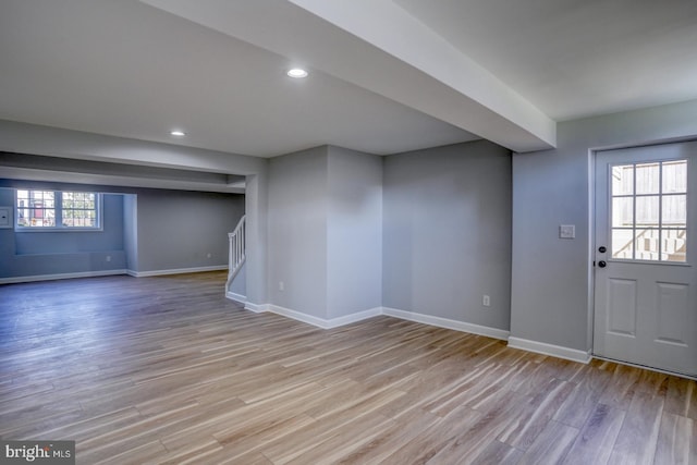 basement with a wealth of natural light and light hardwood / wood-style flooring