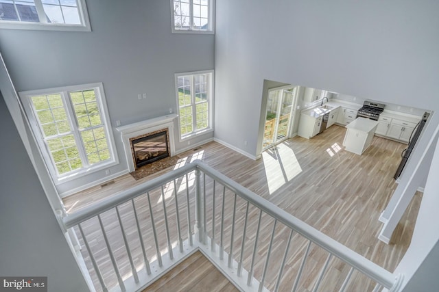 stairway with a premium fireplace, a high ceiling, and hardwood / wood-style flooring