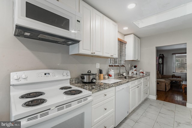 kitchen with sink, dark stone countertops, white cabinetry, and white appliances