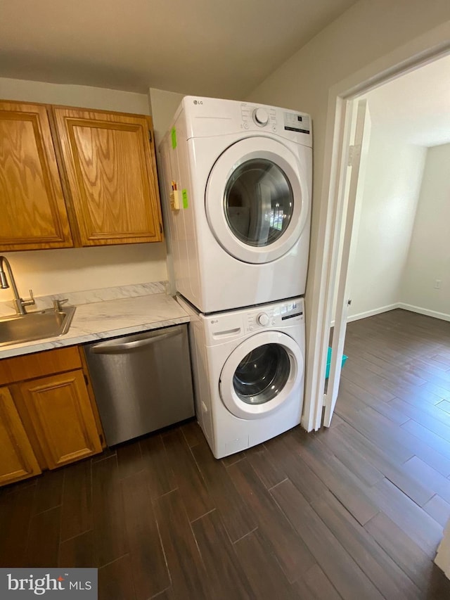 laundry room with stacked washer / drying machine, dark hardwood / wood-style floors, and sink