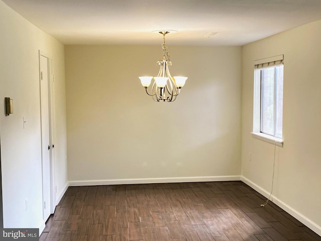 empty room featuring a notable chandelier and dark hardwood / wood-style flooring