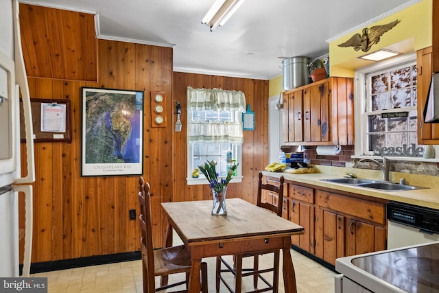 kitchen with dishwasher, crown molding, sink, and wooden walls