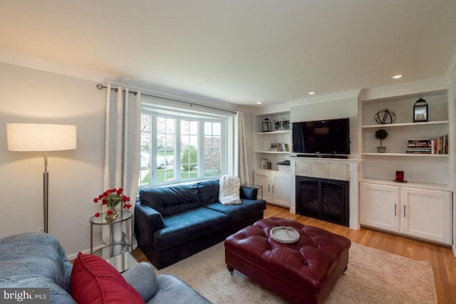 living room featuring ornamental molding, built in shelves, and light wood-type flooring