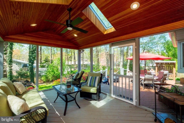 sunroom with vaulted ceiling with skylight, wood ceiling, and ceiling fan