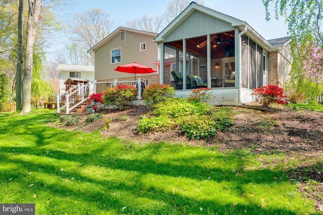 rear view of house featuring a yard and a sunroom