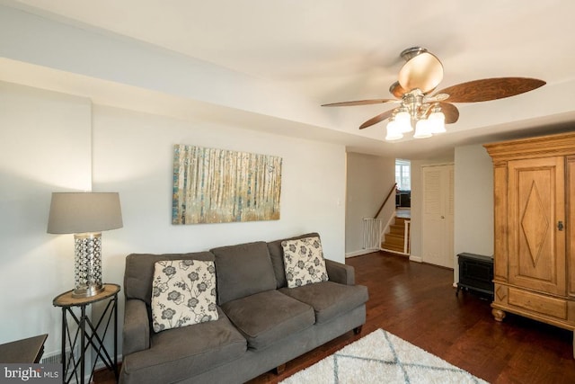 living room featuring ceiling fan and dark hardwood / wood-style floors