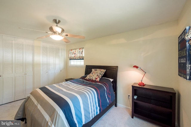 bedroom with ceiling fan, light carpet, and multiple closets