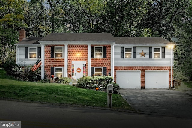 split foyer home featuring a garage and a front yard