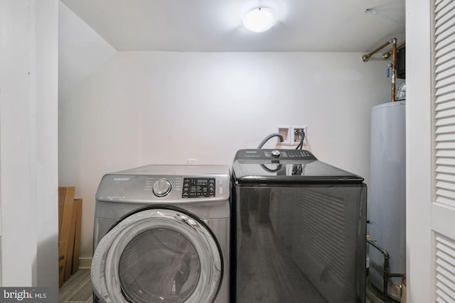 clothes washing area featuring gas water heater, washer and dryer, and hardwood / wood-style floors