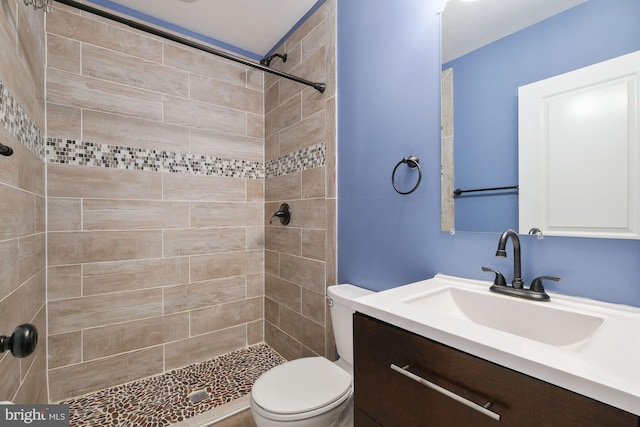 bathroom with a tile shower, vanity, and toilet