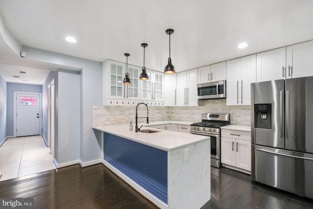 kitchen with dark wood-type flooring, sink, kitchen peninsula, white cabinets, and appliances with stainless steel finishes