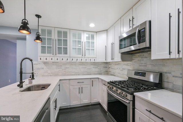 kitchen with decorative light fixtures, sink, light stone counters, stainless steel appliances, and white cabinets