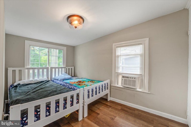 bedroom featuring cooling unit, multiple windows, and hardwood / wood-style floors