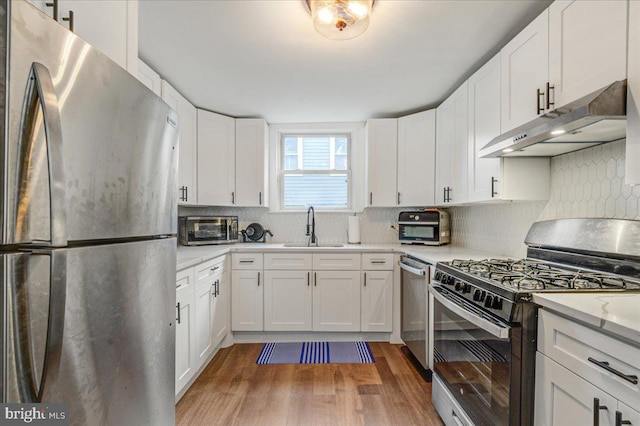 kitchen featuring appliances with stainless steel finishes, dark hardwood / wood-style floors, sink, and white cabinetry