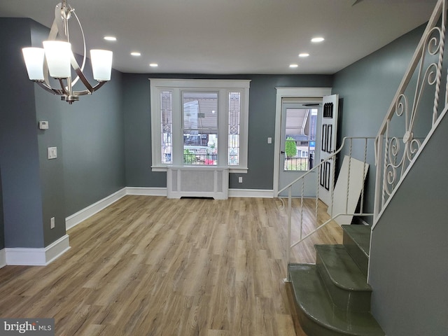 entrance foyer with a notable chandelier, wood-type flooring, and radiator