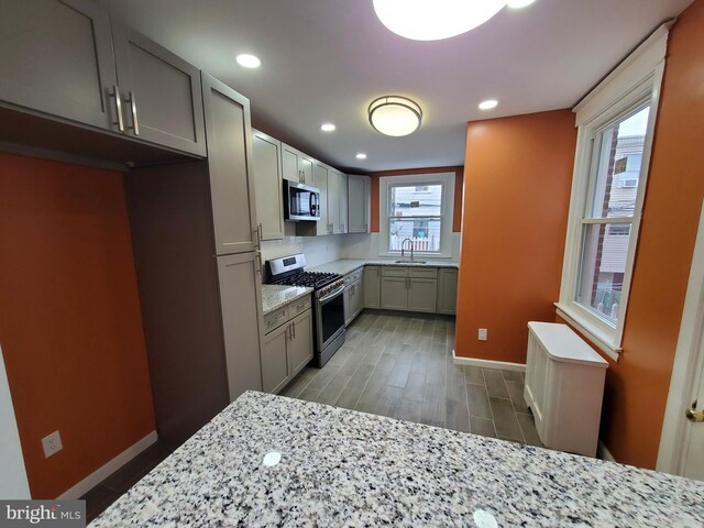 kitchen with light stone countertops, stainless steel appliances, and hardwood / wood-style flooring