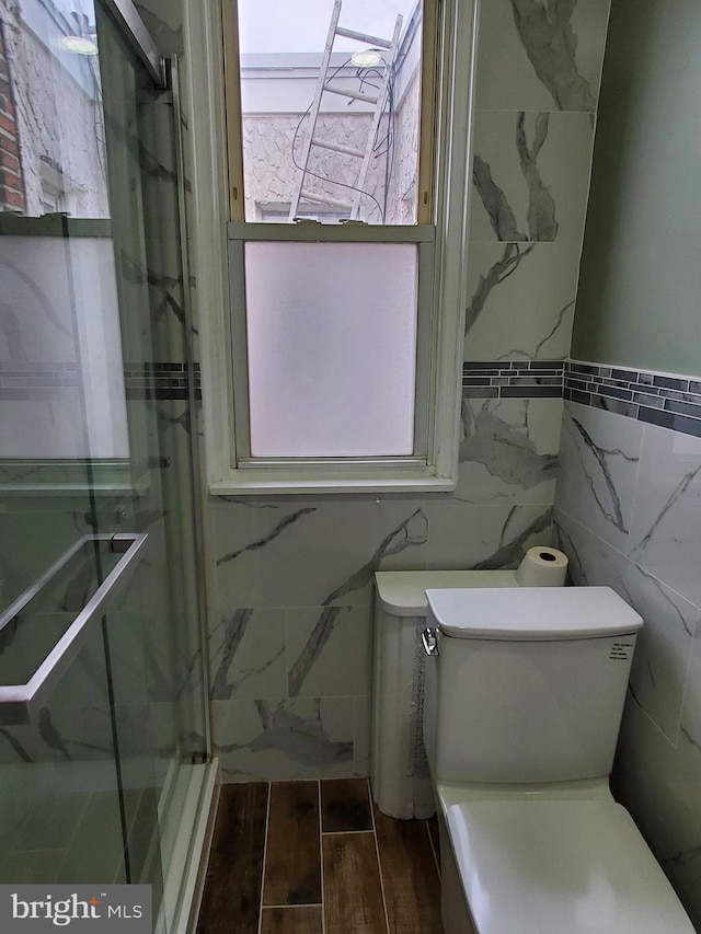 bathroom featuring walk in shower, tile walls, toilet, and hardwood / wood-style flooring