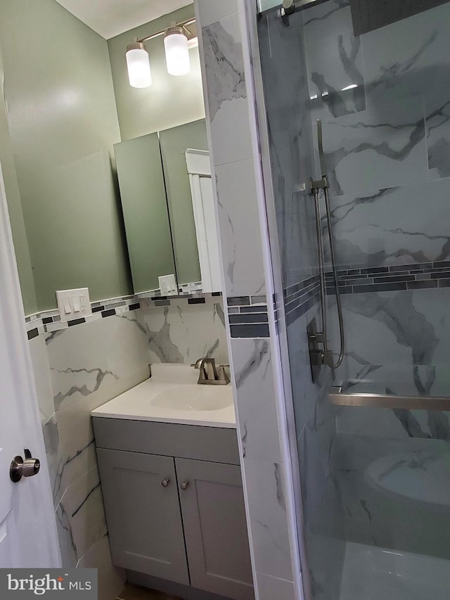 bathroom featuring backsplash, a shower with door, tile walls, and vanity