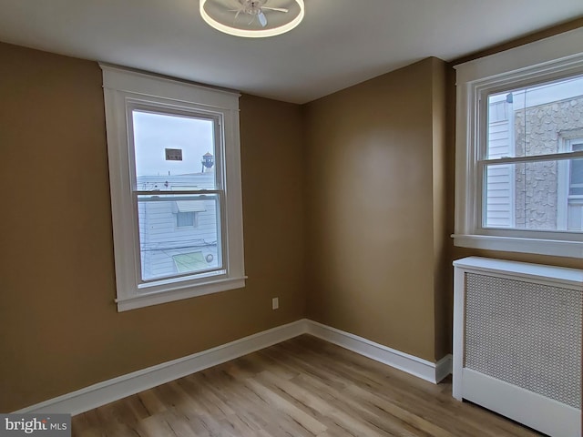 empty room featuring light hardwood / wood-style floors, radiator, and ceiling fan