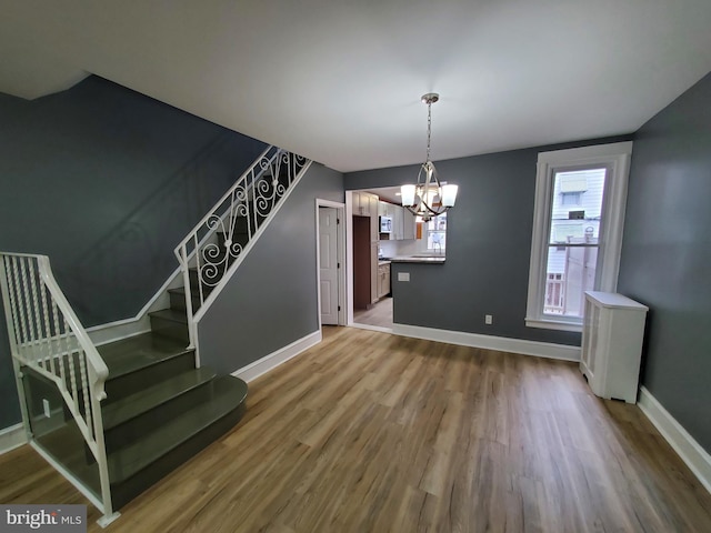 unfurnished dining area with an inviting chandelier and hardwood / wood-style floors