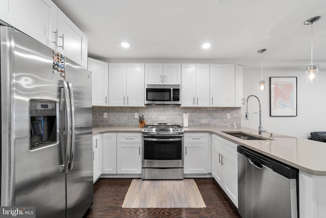 kitchen featuring dark hardwood / wood-style floors, stainless steel appliances, sink, pendant lighting, and white cabinetry