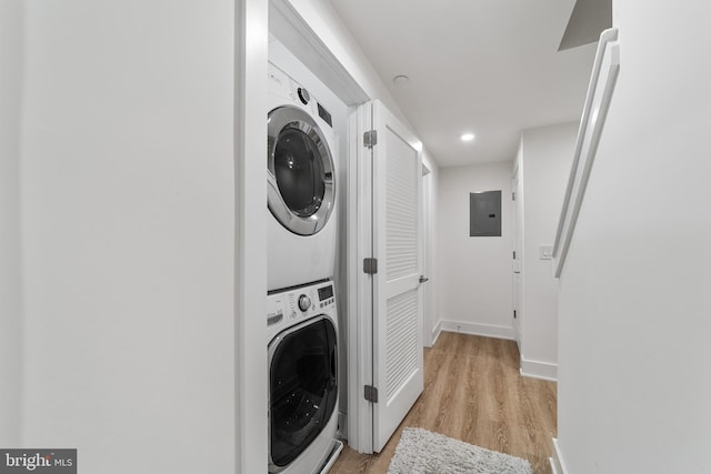 washroom featuring light wood-type flooring, stacked washer / dryer, and electric panel