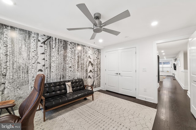 living area featuring dark wood-type flooring and ceiling fan