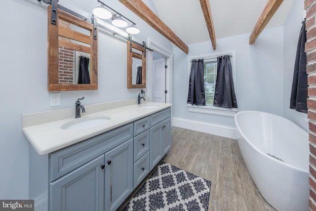 bathroom with beam ceiling, hardwood / wood-style flooring, a washtub, and vanity