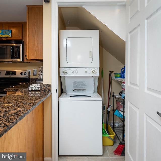 washroom with light tile patterned flooring and stacked washer / drying machine