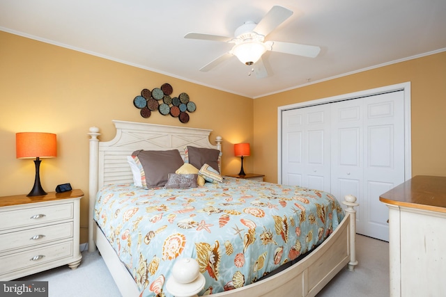 carpeted bedroom featuring ornamental molding, ceiling fan, and a closet