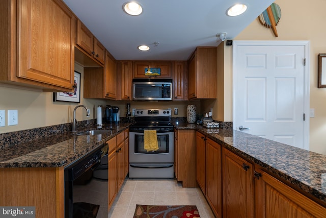 kitchen with stainless steel appliances, dark stone countertops, light tile patterned floors, and sink